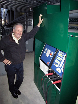 Byron Washom stands next to a control panel for an experiment in which UCSD is testing used EV batteries to see how they would perform as backup energy storage for the grid. Photo by David Ferris