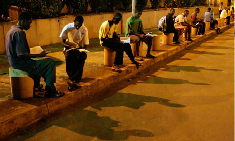 Young Guineans, without access to electricity, study under carpark lights at G'bessi airport in Conakry, Guinea. Photograph: Rebecca Blackwell/AP
